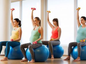 groupe de femmes enceintes faisant de l'exercice avec des haltères sur ballon de fitness