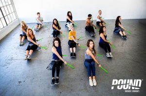 groupe de personnes en séance de pound fitness avec bâtons verts sur sol béton