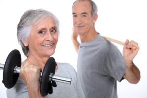 deux seniors souriants pratiquant la musculation avec des haltères