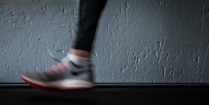chaussure de running en mouvement sur un tapis de course gris