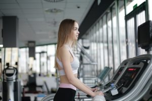 femme sur un tapis de course dans une salle de sport moderne bien éclairée