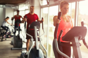 groupe de personnes en salle de sport pratiquant le cardio LISS sur vélos elliptiques