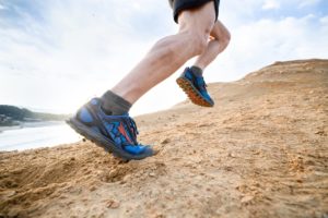 coureur en trail running sur terrain accidenté avec chaussures zéro drop bleues