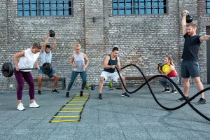 groupe de sportifs en entraînement fonctionnel avec cordes, haltères et échelle de rythme