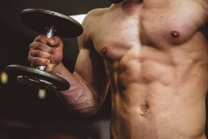 homme musclé tenant un haltère, musculation et fitness pour la santé