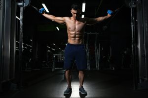 athlète musclé en exercice de musculation avec haltères dans une salle de sport