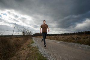 homme qui court sur un chemin de gravier en campagne par temps nuageux