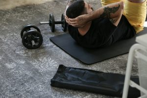 homme effectuant des exercices de musculation avec des haltères sur un tapis de sport