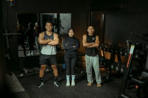 groupe de sportifs en tenue de fitness posant dans une salle avec équipements de musculation et hyrox