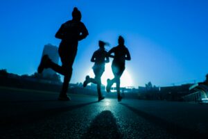 groupe de coureurs en silhouette au coucher de soleil sur route urbaine