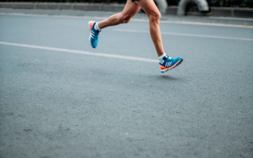 coureur en action portant des chaussures de running bleues et oranges sur piste