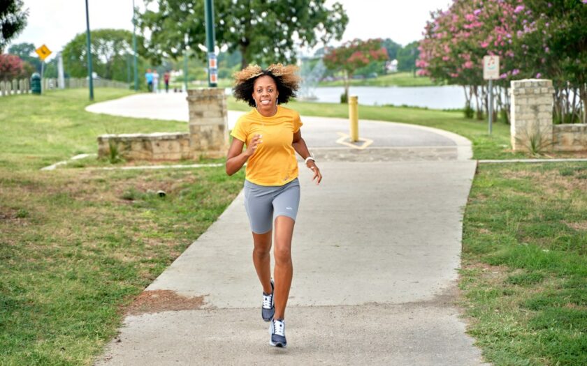 a woman running down a sidewalk in a park