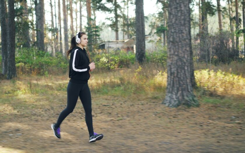 Woman jogging in a forest wearing headphones